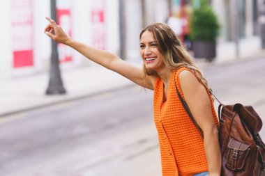 Şehirde taksiye binmek için el sallayan güzel Latin kadın.