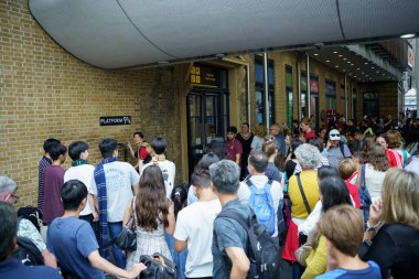 Londra, İngiltere, 20 Temmuz 2024. Japon gençler ellerinde değnek varmış gibi davranıp Harry Potter tramvayı ile Kings Cross istasyonunda 9-4 numaralı hayali platformda fotoğraf kuyruğuna girdiler..