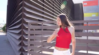 Şık bir kadın modern mimarinin arka planına karşı özgüvenle duruyor, modern modanın güzelliğini ve çevresindeki kentsel hayatın canlı enerjisini sergiliyor.