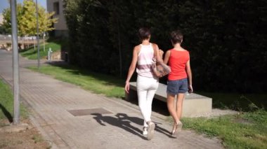 İki kadın mutlu bir şekilde birlikte parkta gezintiye çıkıyorlar. Parlak, sıcak günışığıyla dolu güzel bir günde. Birbirleriyle güzel bir dostluk ve rahatlama anı yakalıyorlar.