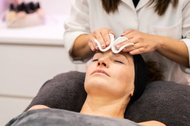 Güzellik salonunda cilt bakımı sırasında pamuk pedi kullanan tanınmayan kadın güzellik uzmanı.