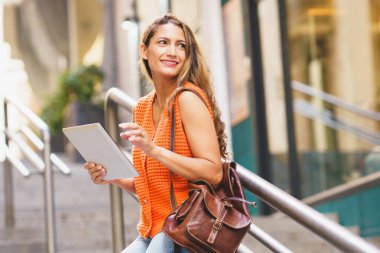Kentte duran tablet kullanan Latin bir kadının yan görüntüsü.