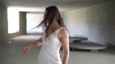 Güzel tasarlanmış, minimalizmle karakterize edilmiş modern bir mekanda genç bir kadın sanatın ve hareketin özünü gözler önüne sererek kendini zarif ve akışkan bir dans performansıyla ifade eder.