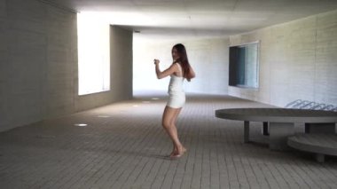 Modern bir mimari ortamda zarif ve dengeli bir kadın zarafetini ve özgüvenini sergilerken ışıl ışıl ve parlak bir koridorda güzelliğin özünü temsil ediyor.