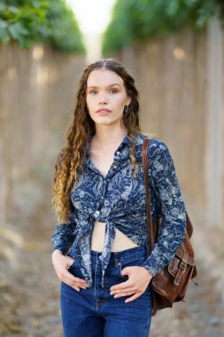 Tarz sahibi ve kendine güvenen genç bir kadın dışarıda durur, cazibe ve zerafet saçarak arkadaşlarıyla gündelik geziler için mükemmel bir kıyafet sergiler ya da doğada huzurlu bir gün geçirir.