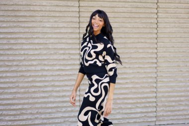 Kafkasyalı mutlu bir sanatçının serbest dans ederken ve şehirde gülümserken üç çeyrek boy fotoğrafı.