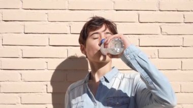 Genç bir çocuk hareketli bir tuğla duvarın önünde düşünceli bir şekilde duruyor. Etrafındaki dünyayı merak ve merakla özetleyen sakin bir iç gözlem anını ve derin yansımasını yakalıyor.