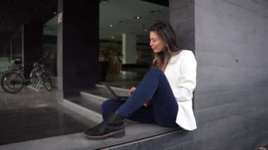 Modern ofis alanındaki merdivenlerde şık bir genç kadın, yaratıcılık ve ilham saçarak profesyonellik ve zarafeti harmanlayarak dizüstü bilgisayarına odaklanıyor.