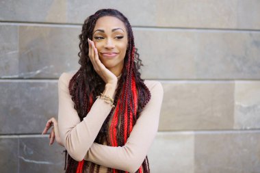 Canlı ve göz alıcı saçları olan kendine güvenen bir kadın zarif, modern bir arka plana karşı zarif bir poz verir. Havalı bir stil ve cazibe yayar. Olağanüstü özgüvenini ve farklı bireyselliğini sergiler.