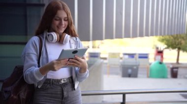 Açık hava ortamında, son derece şık bir kadın kendine güvenen bir tablet tutuyor, kendine güvenen bir havayla bakıyor ve çevredeki herkese ilham veriyor.