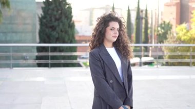 Şık ve kendine güvenen genç bir kadın, profesyonelliği ve çağdaş moda eğilimlerini güzel bir şekilde somutlaştıran şık ve zarif bir ceket giyerek dışarıda duruyor.