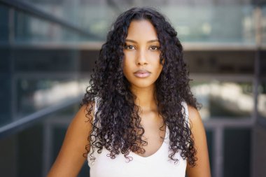 Enerjik bir şehir ortamında, kendine güvenen kıvırcık saçlı genç bir kadın dikkat çekiyor. Güç ve zarafetiyle büyüleyici kişiliği ve manyetik varlığıyla izleyicileri büyülüyor.