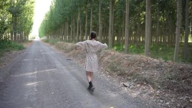Bir kadın, uzun ağaçlarla çevrili güzel, güneşli bir çakıl yolunda neşeyle yürür. Doğanın ve yaşamın güzelliklerinin tadını çıkarırken özgürlük ve sükûnet hissini somutlaştırır.