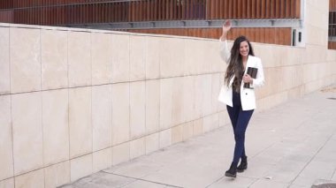 Moda ve kendine güvenen bir kadın, şehir yaşamını gözler önüne seren canlı çağdaş mimari bir zemine karşı modern tarzı somutlaştıran hareketli bir şehir bölgesinde güven içinde dolaşır.