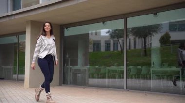 Şık ve kendine güvenen bir kadın dikkat çeken çağdaş mimari unsurlarla şehir modasını kusursuz bir şekilde harmanlayan çarpıcı bir modern cam binanın önünde yürür.