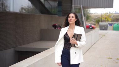 Şık ve kendine güvenen bir kadın hareketli bir şehir ortamında, modern moda unsurlarını güncel eğilimleri yansıtan canlı çağdaş bir arka plana karşı zarif bir şekilde sergiliyor.