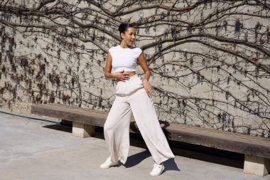 Yetenekli bir dansçı zarif ve çarpıcı bir poz sergiliyor. Güzel dokulu bir duvara karşı mükemmel bir şekilde dizilmiş, sanattaki zarafet ve dinamik hareketin gerçek özünü somutlaştırıyor.