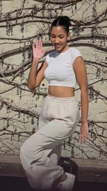 Canlı ve hayat dolu bir kadın günlük beyaz elbiseleriyle neşeli bir şekilde dans eder, coşkulu enerjisini ve tutkusunu sanatsal bir arkaplan karşısında sergiler ve bu onun hareketlerini güçlendirir.