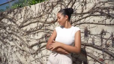 Şık bir genç kadın, çarpıcı bir doğal zemine karşı şık bir kıyafet içinde pozitiflik ve enerji dolu sıcak, güneşli bir yaz atmosferinde güven ve neşe saçar.