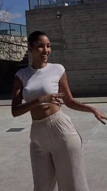 Modaya uygun genç bir kadın şık ve modaya uygun kıyafetlerini gururla sergilerken açık havada poz veriyor, kendine güveni, zarafeti ve şık bir stili var.