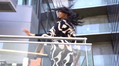 Sokakta dans eden genç siyahi kadın, çok gösterişli kıyafetler giyiyor. Gençlik hayatı ve iyi titreşimler kavramı.