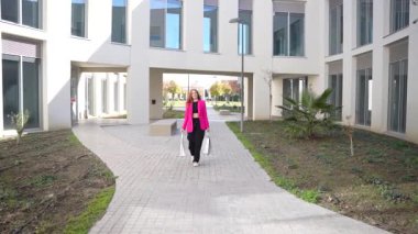 Şehir ortamında, şık giyimli bir yaya, temiz mimari çizgiler ve sanatsal peyzajlarla çevrili iyi tasarlanmış bir meydanda yürüyor ve şık bir atmosfer yaratıyor.