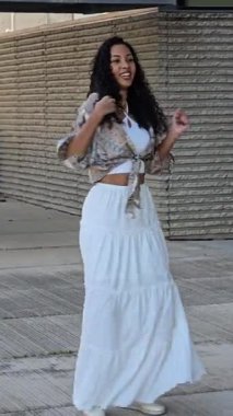 Modayı takip eden genç bir kadın modaya uygun bir medya yayını için ideal hale getiren zarafet ve doğal yeteneğin mükemmel bir karışımını sergileyen modaya uygun bir kıyafetle açık havada poz veriyor.