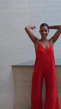 Şık ve modaya uygun bir model canlı, göz alıcı kırmızı bir elbise içinde çağdaş, minimalist bir arka plana karşı durarak modern moda ve zamansız zarafetin mükemmel bir karışımını sergiliyor.