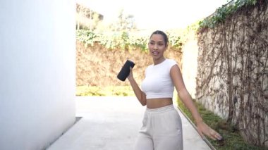 Modayı takip eden genç bir kadın, elinde kamerayla dışarıda poz veriyor ve şık, modern bir ortamın tadını çıkarırken, hareketli kişiliğini sergiliyor.