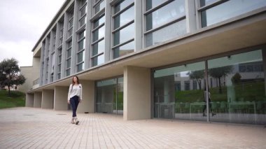 Yetenekli bir patenci, çarpıcı bir çağdaş binanın önünde poz verir. Büyük cam pencereler ve zarif bir tasarım sergiler. Canlı bir şehir manzarası içinde mükemmel bir konuma sahiptir.