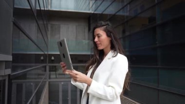 Genç bir kadın, teknolojinin ve yaşam tarzının karışımını, yaratıcılığı, hareketliliği ve yeni bir dijital bağlantı çağını yansıtan modern şehir ortamında tabletine güvenle bağlanır.