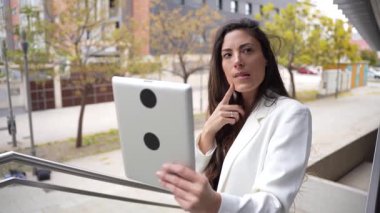 Yetenekli profesyonel bir kadın sanal bir toplantı için tablet kullanırken açık havadan zevk alıyor, modern iş hayatı dengesi kavramını günümüzde hızlı iş sahası olarak gösteriyor.