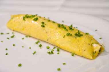 Beyaz tabakta yeşil otlu Fransız omleti, sütlü yumurta veya Baveuse yumurtası.