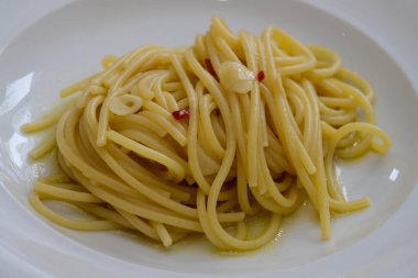 Sarımsaklı spagetti Colatura di Alici ve beyaz tabakta peperoncini.