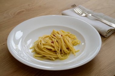 Sarımsaklı spagetti Colatura di Alici ve beyaz tabakta peperoncini.