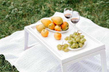 Durgun hayat. Ahşap bir masada iki bardak kırmızı şarap ve meyve. Dışarıda romantik bir akşam yemeği.. 