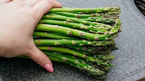 Asparagus. Fresh asparagus. Bouquet of green asparagus close-up. A womans hand holds a bunch of juicy fresh asparagus.