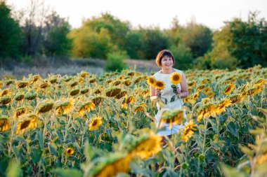 Doğanın tadını çıkaran güzel, genç bir esmer. Ayçiçeği tarlasında elinde buketle mutlu bir esmer.. 