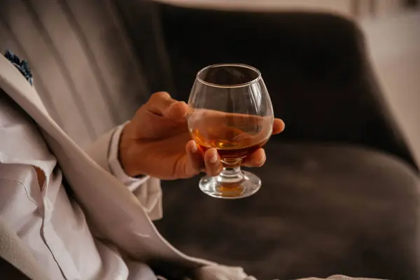 Bir adamın elinde bir bardak konyak. 