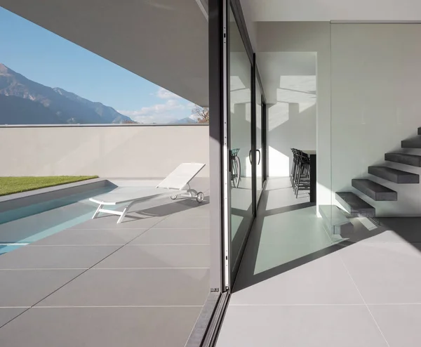 内饰现代化别墅 有悬臂楼梯和宽敞的屋顶 外面是一个游泳池 上面有一张甲板躺椅 用来放松身心 瑞士阿尔卑斯山的阳光灿烂的一天 里面没有人 — 图库照片