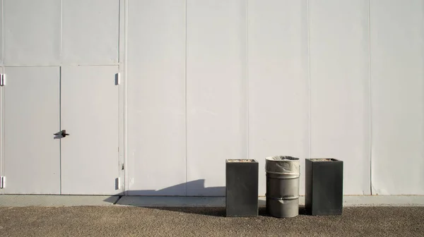 工业园区内有白色墙背景的两个巨大烟灰缸之间的一个垃圾桶 — 图库照片