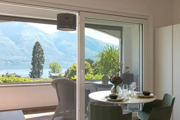 一个漂亮公寓的内部 这里有两张椅子 一张桌子上摆满了各种食物 可以饱览瑞士的自然 高山和湖泊 里面没有人 — 图库照片