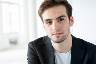 Sakallı, siyah ceketli ve beyaz gömlekli bir çocuğun portresi. Arkasında bir ışık penceresi var..