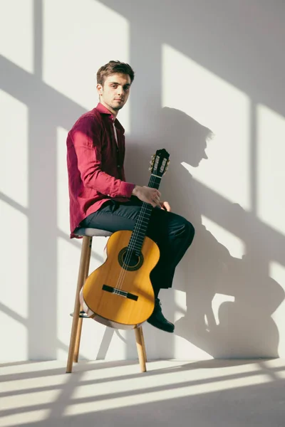 Niño Está Sentado Taburete Sosteniendo Guitarra Con Una Mano Lleva — Foto de Stock