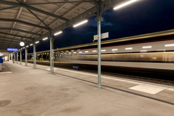 Led照明で照らされた屋根付きの駅ホーム 列車はフルスピードで通過する 誰も中にいない — ストック写真