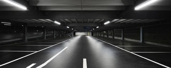 シーンを照らすランプ付きのモダンな地下ガレージ 駐車場は床に描かれています 誰も中にいない — ストック写真