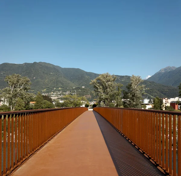 현대식녹슨 다리의 보행자와 자전거로 앞쪽에 보이며 뒤에는 티치노에 스위스 알프스가 — 스톡 사진
