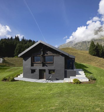 Çok sıra dışı bir İsviçre dağ evi çünkü siyah ve ahşaptan yapılmıştır. Etrafı güzel yeşil bir yaz otlağıyla çevrili. Gökyüzü mavi ve sessiz ve huzurlu bir yere benziyor..