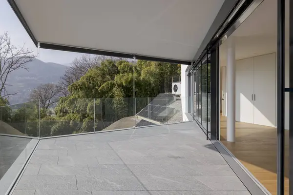 Large terrace of a new modern flat with a view of nature. The floor is made of stone.