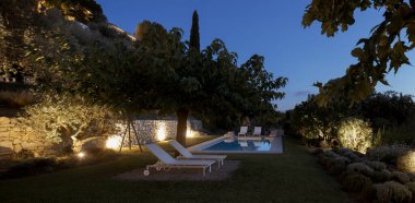 Mavi yüzme havuzu ve güneşlenmek için beyaz salonları olan güzel bir bahçe. Güneş çoktan battı. İçeride kimse yok.